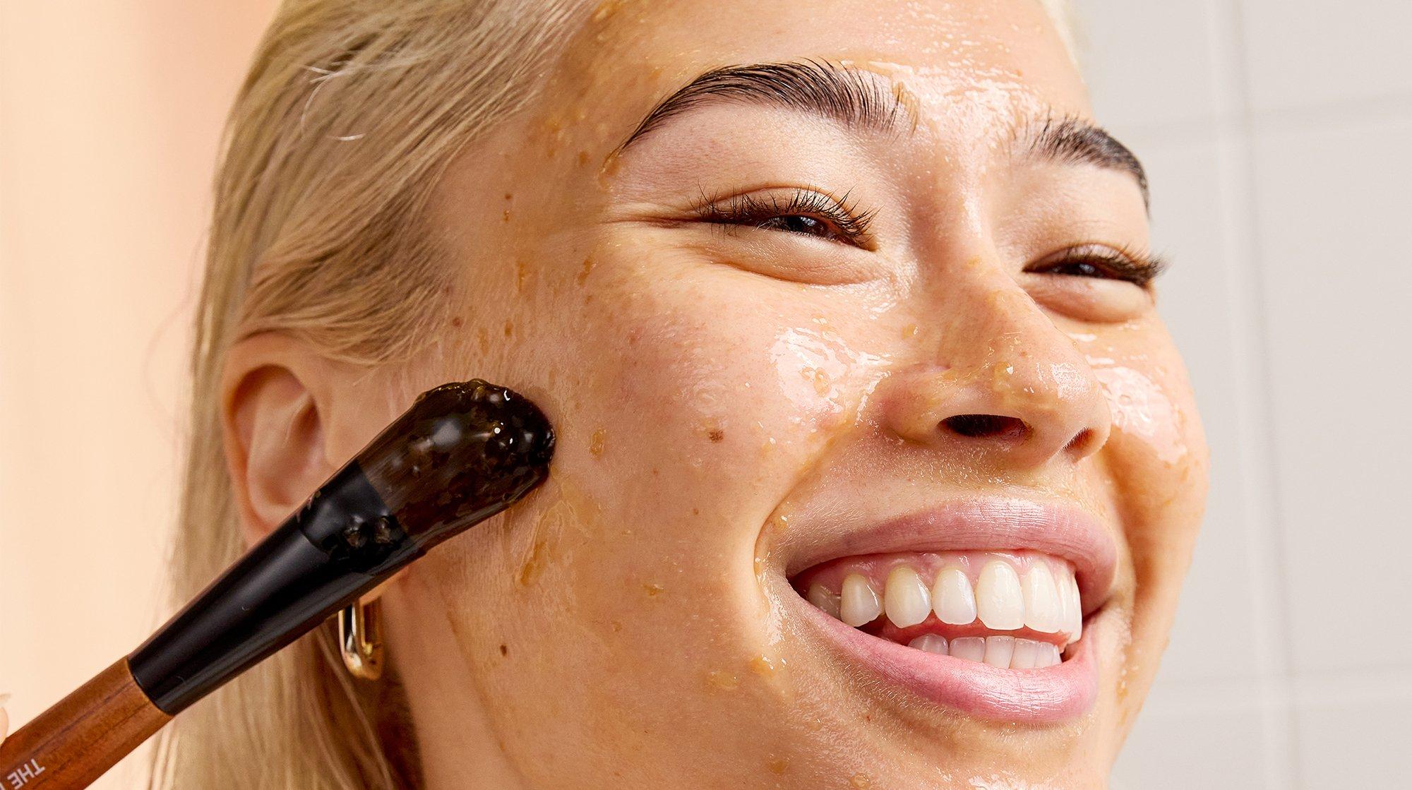 a woman with a brush on her face smiling