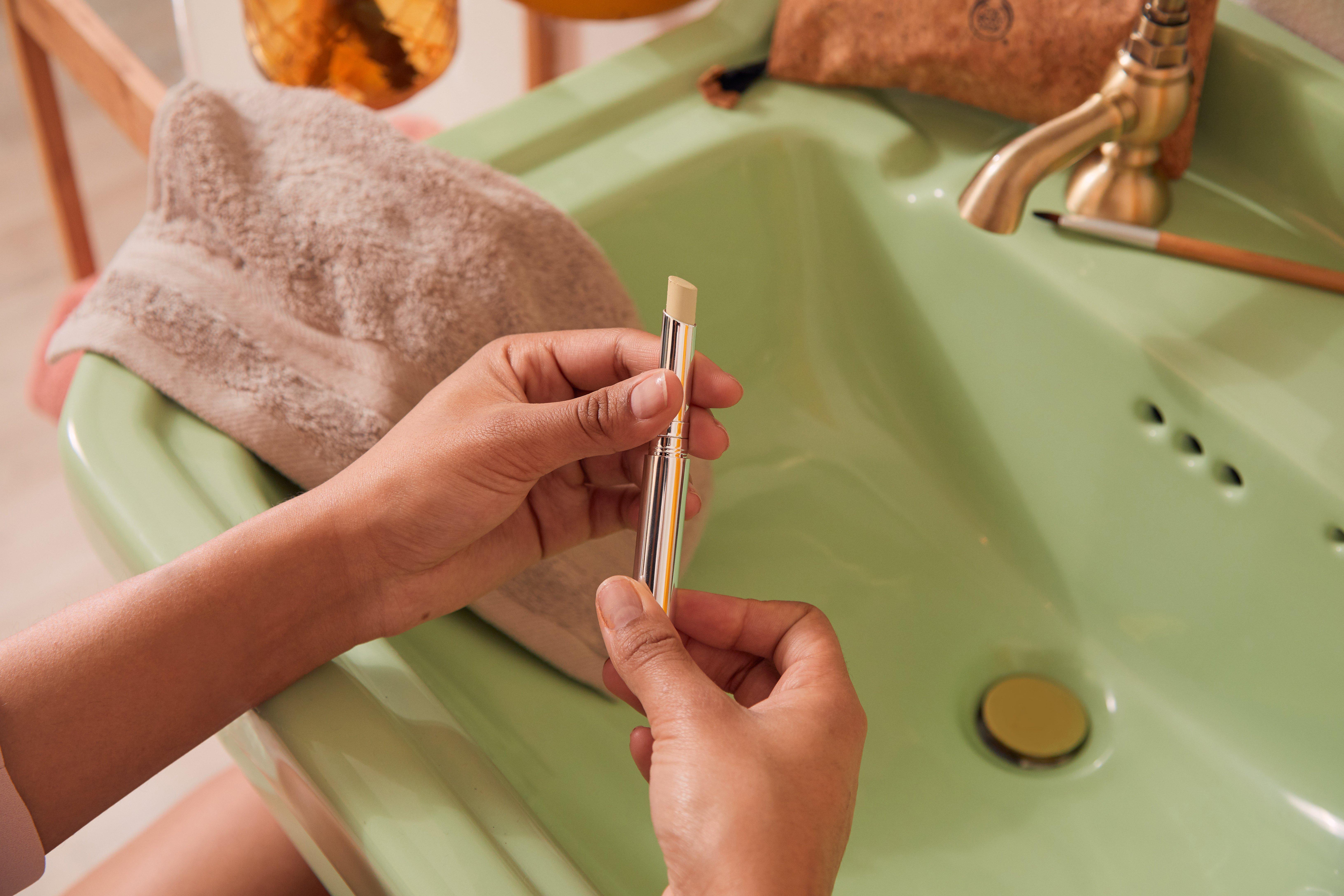 Unas manos sostienen corrector de The Body Shop