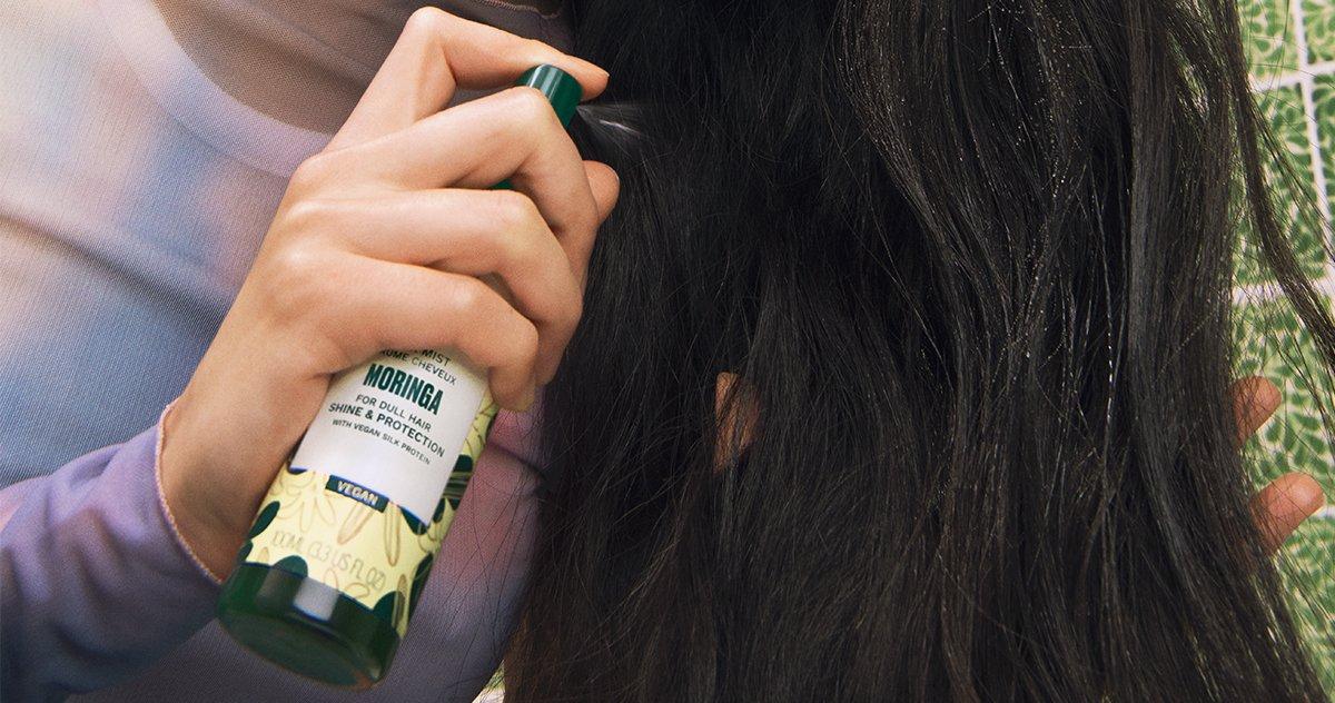 Person applying Moringa Hair Mist to their hair