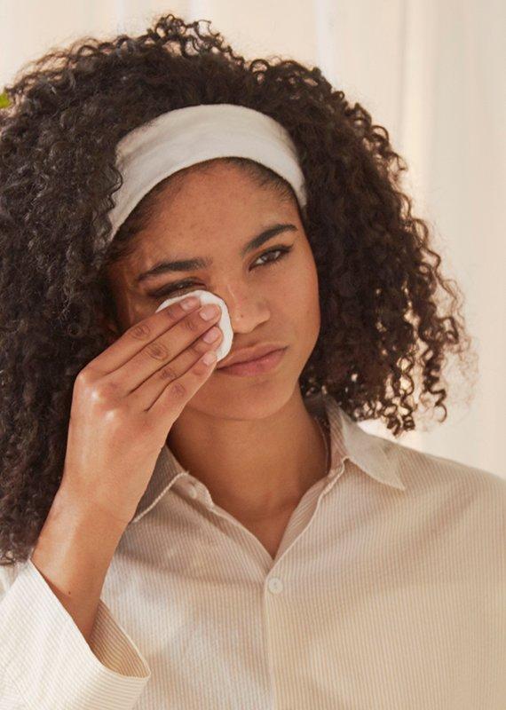 Woman cleansing face with cotton pad