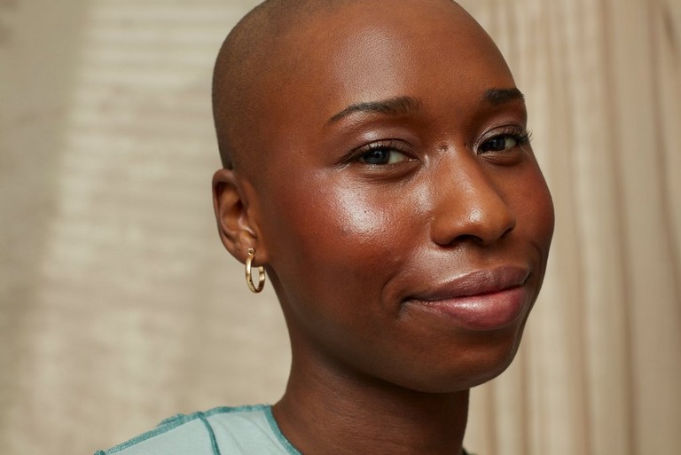a woman with a shaved head and earrings posing for a picture