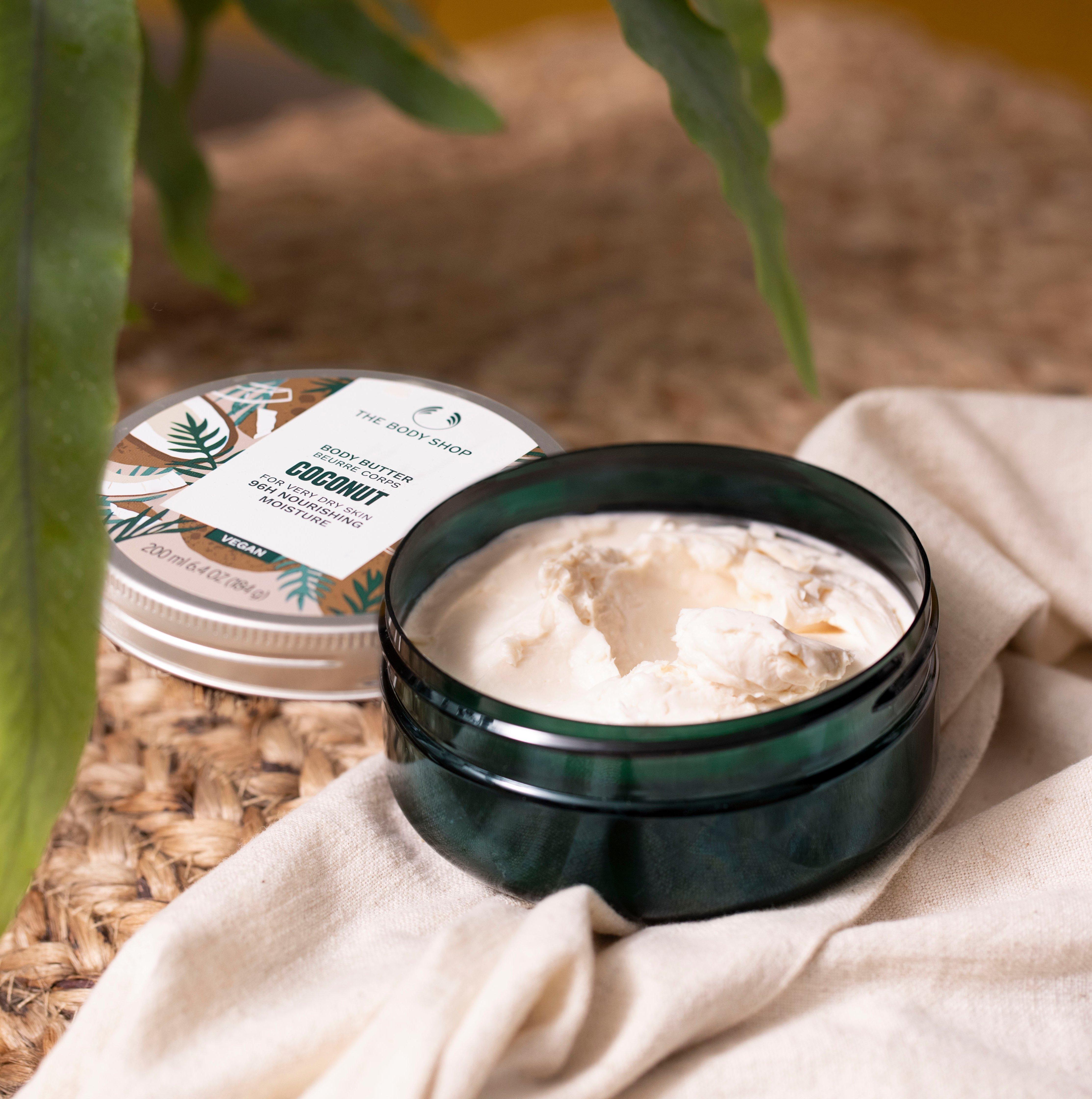 Hands scooping The Body Shop Coconut Exfoliating Body Cream