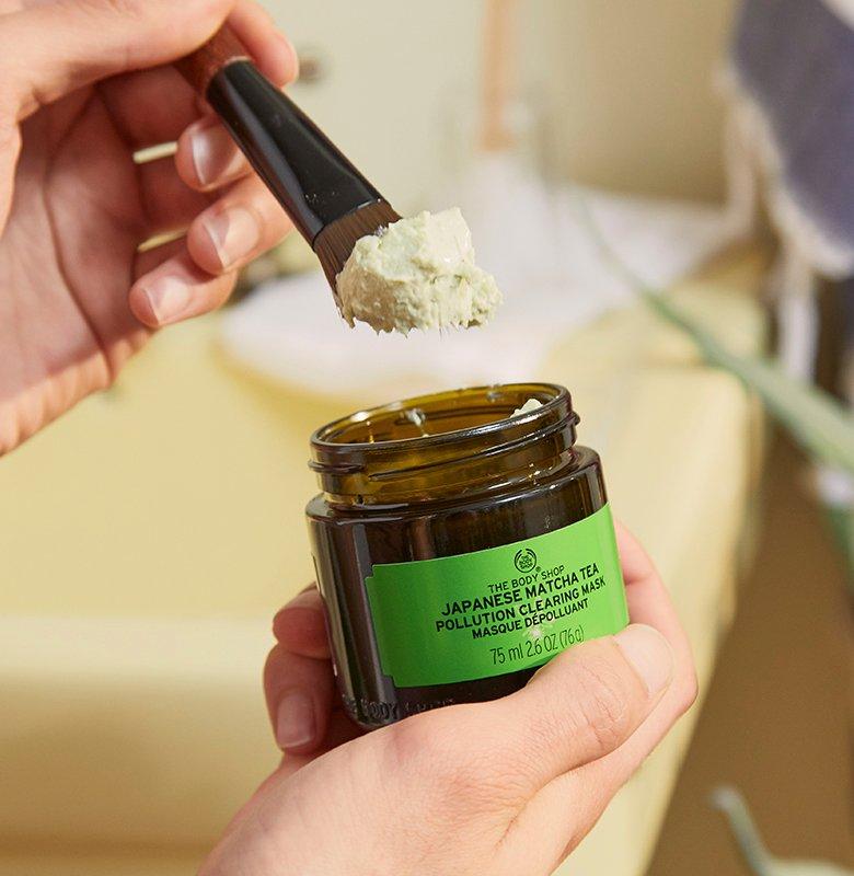 Face mask brush being dipped into Japanese Match Tea Pollution Clearing Mask