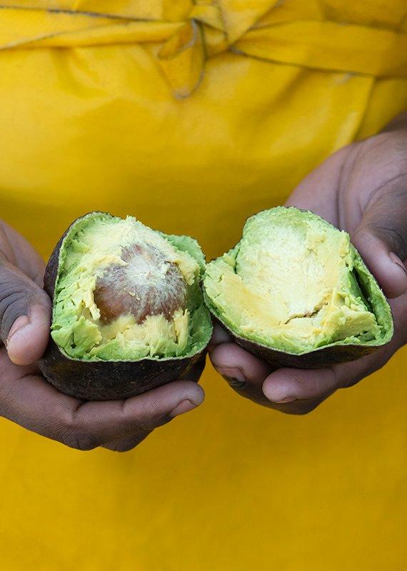 Woman holding an avocado cut in half