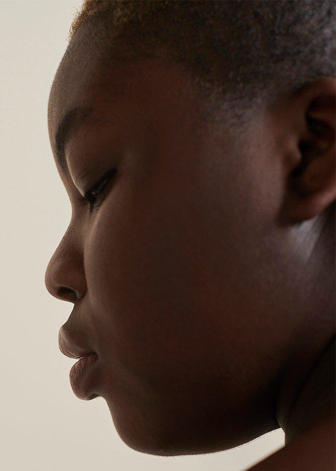 Model looking away from the camera against a beige backdrop