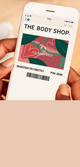 Woman holding phone. On the screen there is a pink floral The Body Shop gift card. Woman holding phone. On the screen there is a pink floral The Body Shop gift card.