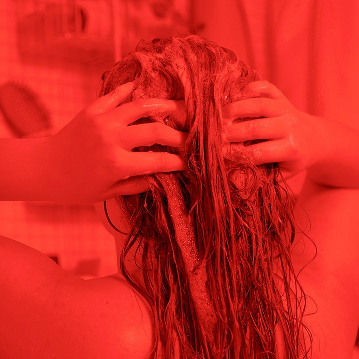 Woman shampooing her hair with a red filter on the image