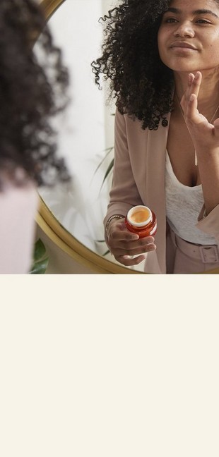 Model applying face cream in mirror Model applying face cream in mirror
