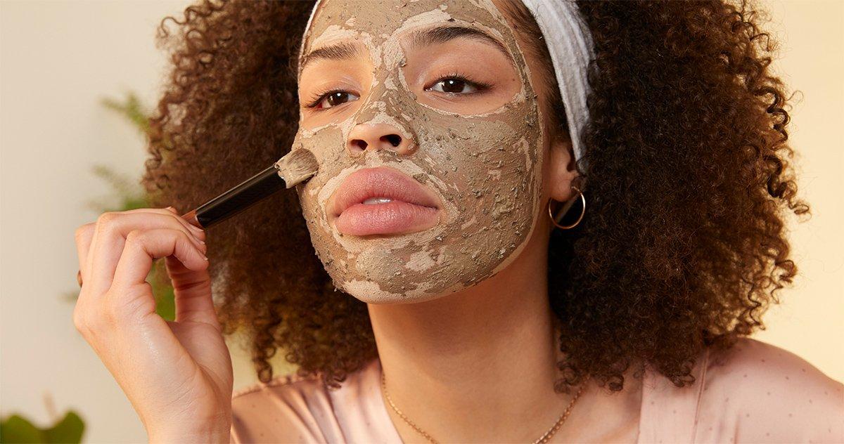 Model applying Himalayan Charcoal face mask with a brush