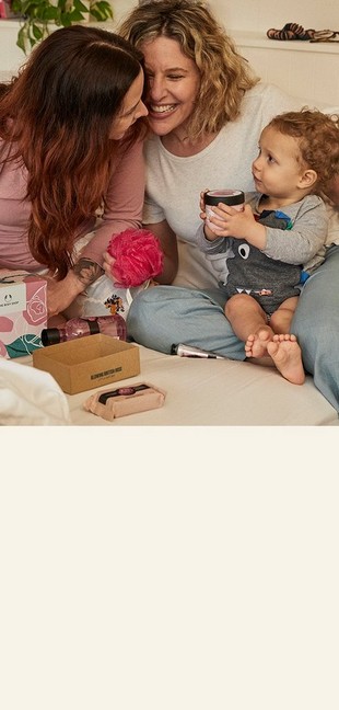 Two mothers' exchanging gifts with their baby son sat in the middle Two mothers' exchanging gifts with their baby son sat in the middle