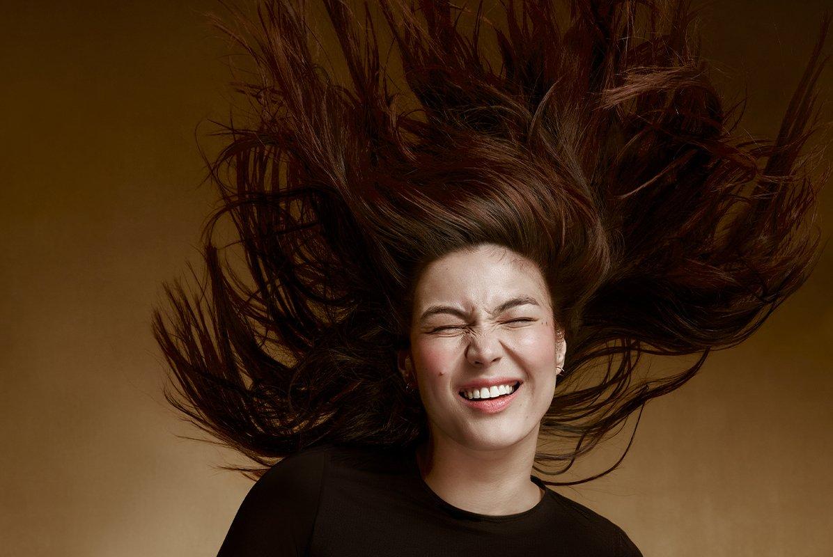 a woman with a black shirt and wind blowing her hair 