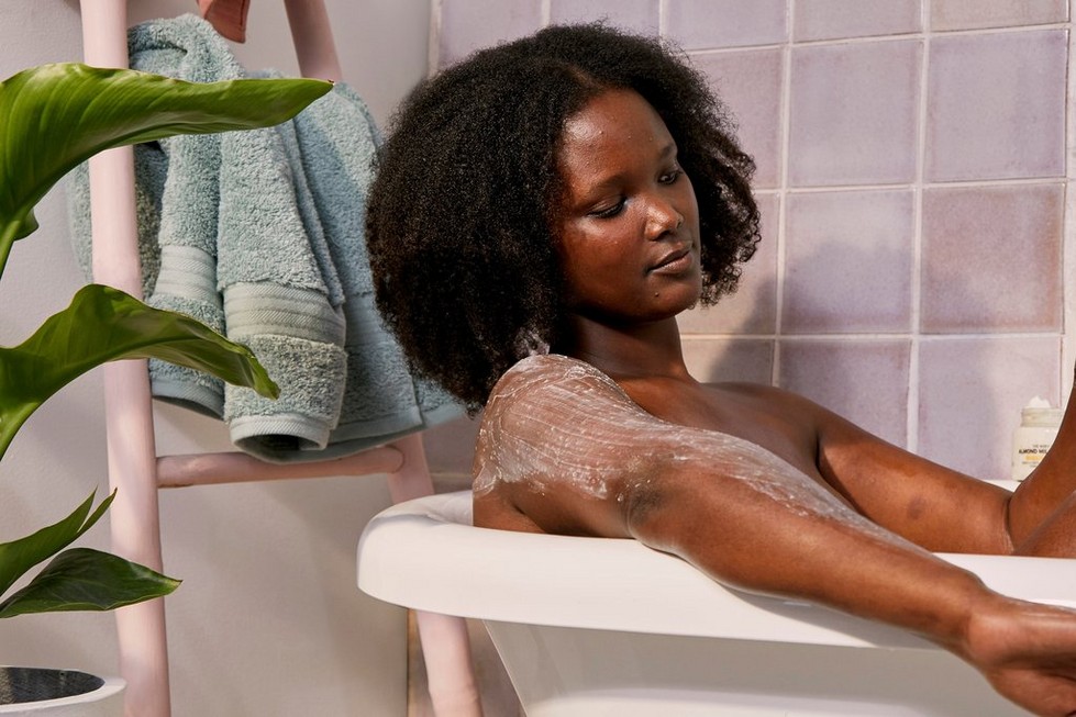 Woman applying exfoliating cream whilst in the bath Woman applying exfoliating cream whilst in the bath