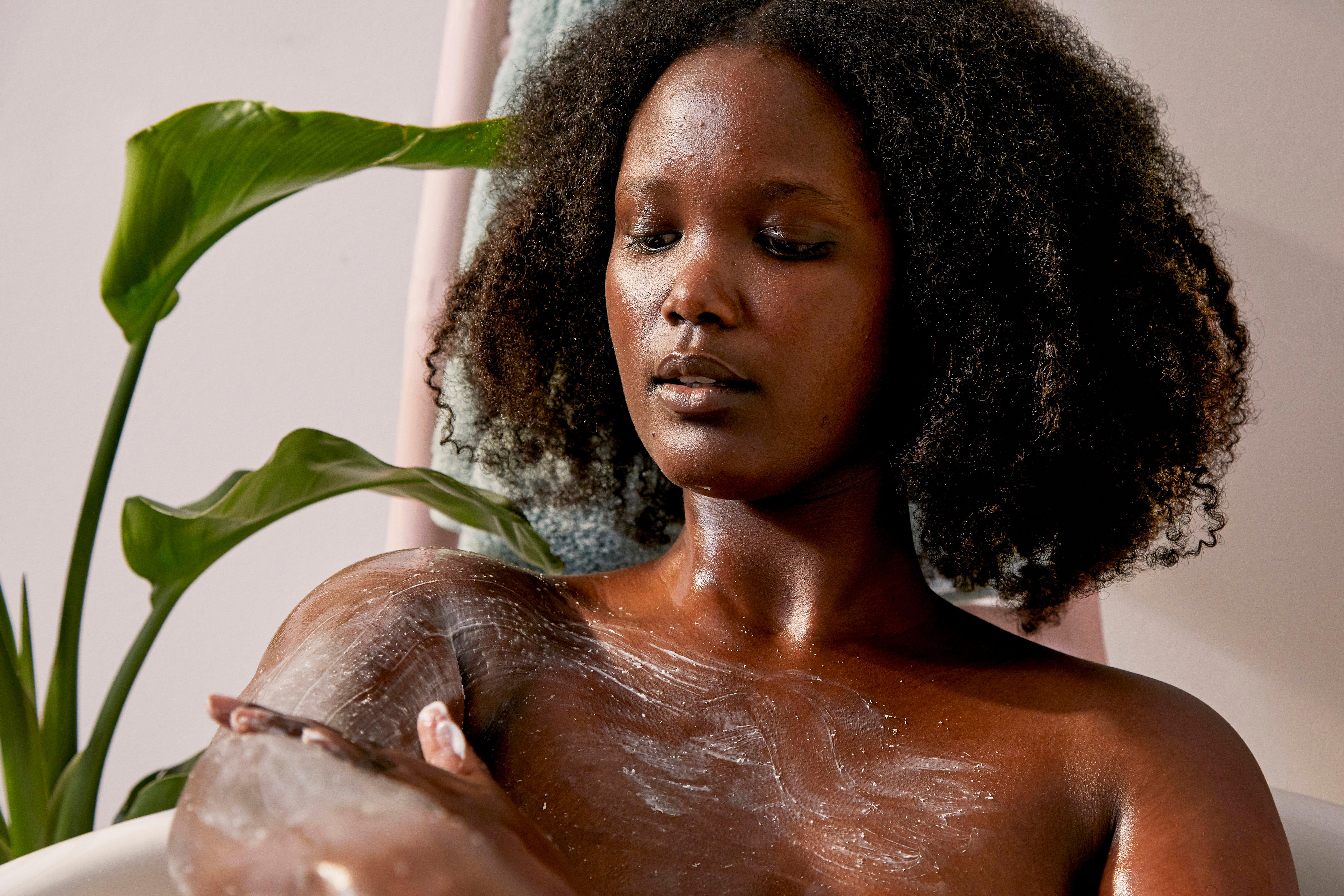 Woman applying The Body Shop Almond Scrub