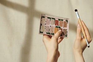 Des mains tenant une palette de maquillage et un pinceau Des mains tenant une palette de maquillage et un pinceau