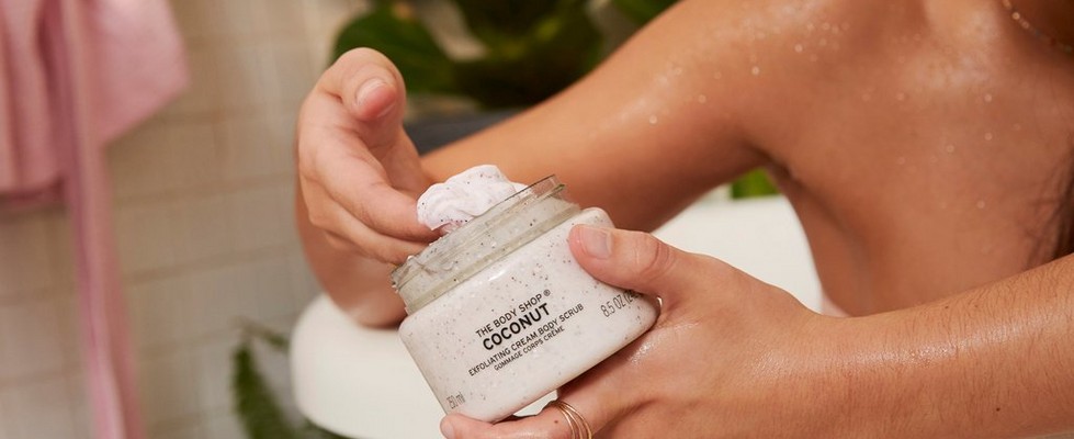 Hände beim Entnehmen von Coconut-Peelingcreme von The Body Shop Hände beim Entnehmen von Coconut-Peelingcreme von The Body Shop