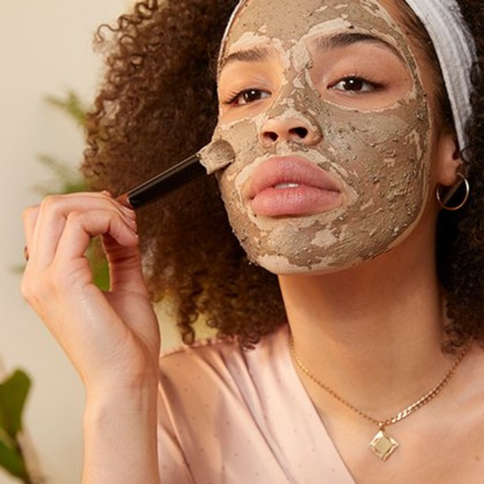 Model applying a face mask to face Model applying a face mask to face