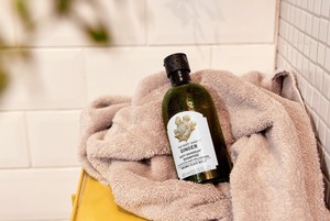 Flasche mit Ginger Shampoo von The Body Shop auf einem Handtuch Flasche mit Ginger Shampoo von The Body Shop auf einem Handtuch