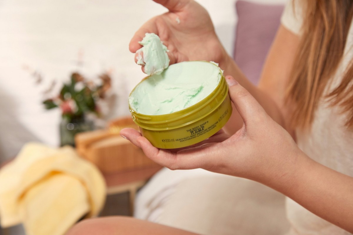 Woman scooping The Body Shop Hemp Body Butter from tub