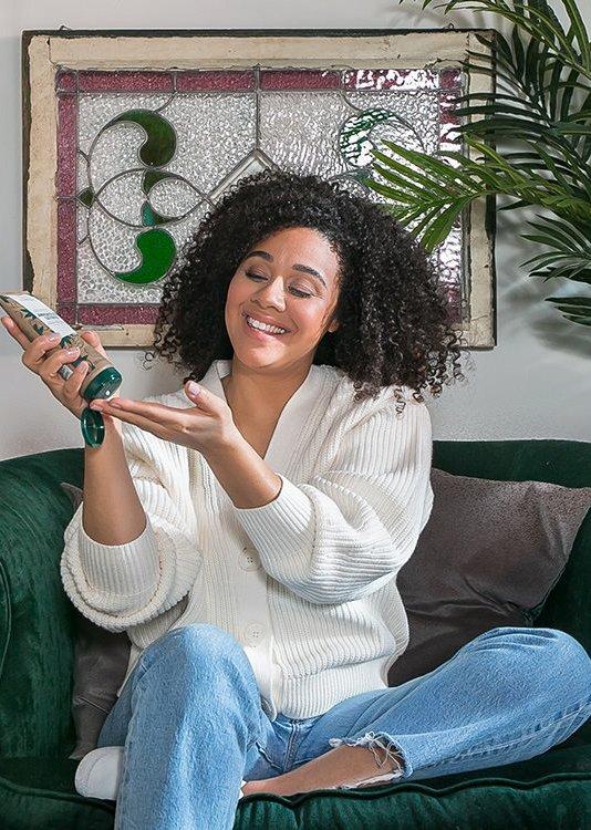 A woman holding The Body Shop's Jamaican Black Castor Oil product for hair