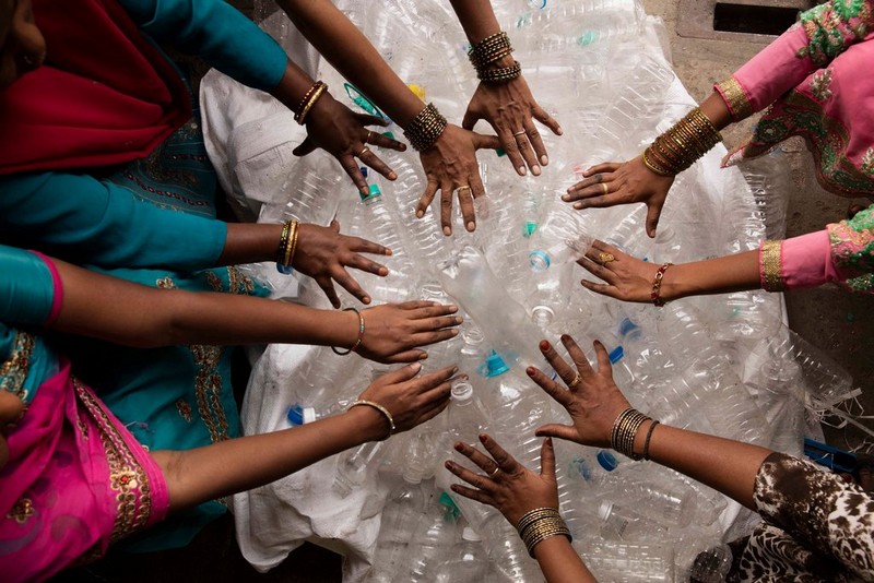 Group of people with hands over plastic bottles in a circle Group of people with hands over plastic bottles in a circle