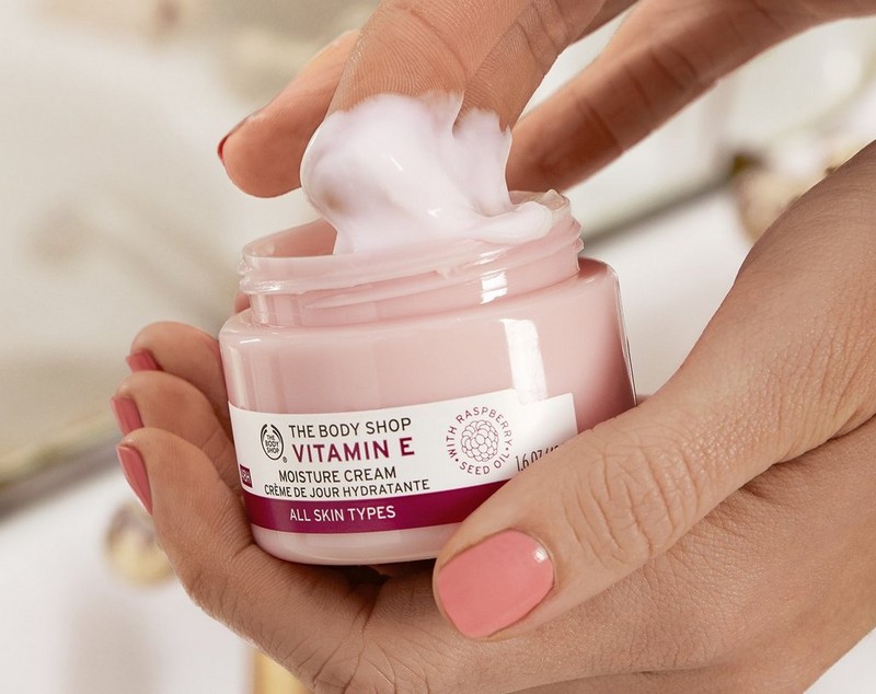 Unas manos sacando producto de un bote de Crema de Día de Vitamina E Unas manos sacando producto de un bote de Crema de Día de Vitamina E