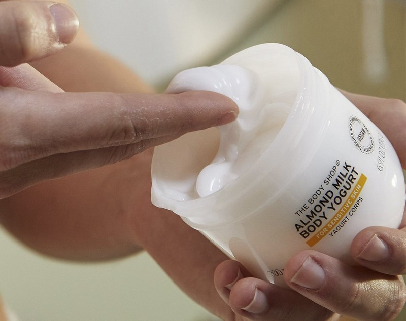 Manos sacando producto de un Body Yogurt de Almendra Manos sacando producto de un Body Yogurt de Almendra