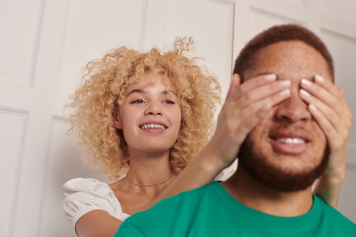 woman covering mans eyes as a surprise