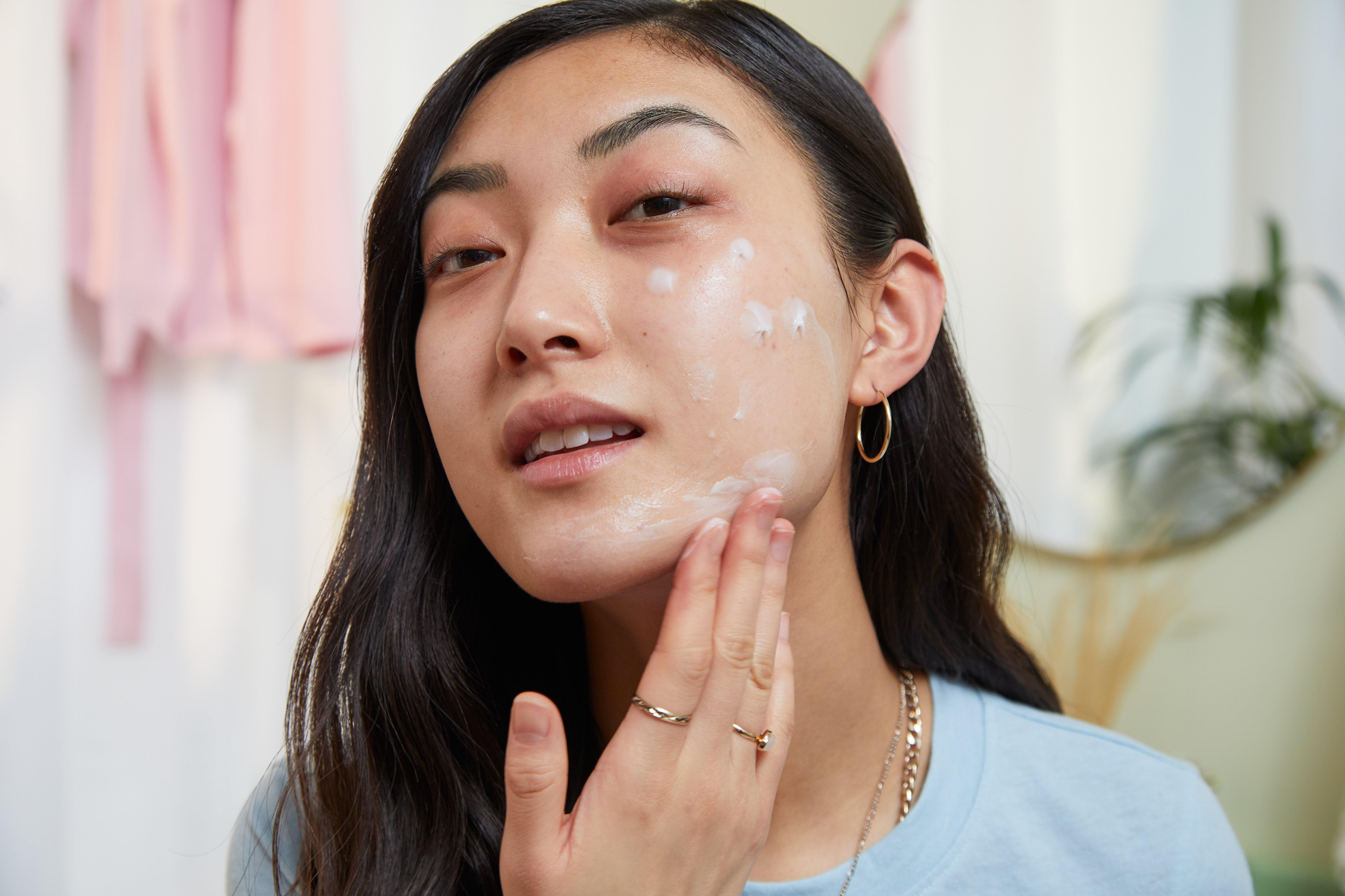 Woman applying face moisturiser